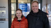 Pariskunta hymyilee vierekkäin Kelan konttorin edustalla.