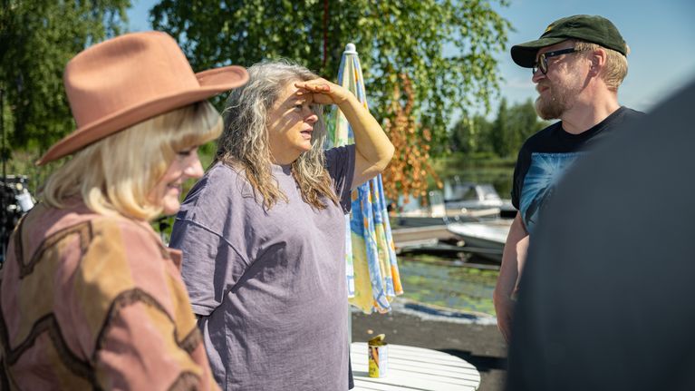 Etualalla Pirjo Lonka cowboy-hatussa. Elina Knihtilä juttelee Teemu Nikin kanssa suojaten kädellä kasvoja auringolta.