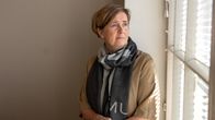 Anna-Mari Ahonen istuu ikkunalaudalla ja vakavana ulos ikkunasta.