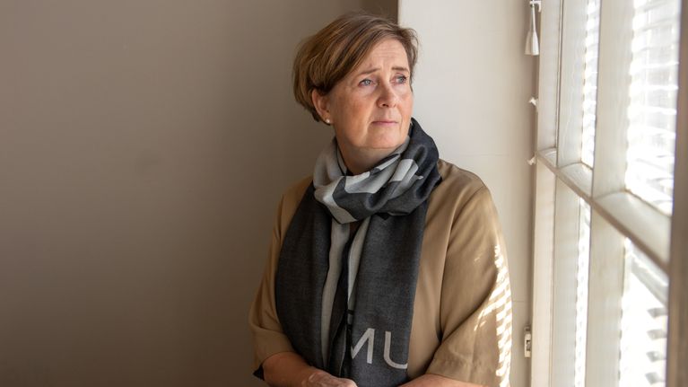 Anna-Mari Ahonen istuu ikkunalaudalla ja vakavana ulos ikkunasta.