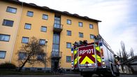 Brandbil står parkerad på innergården till ett gulaktigt höghus. Dörren till det närmaste trapphuset står på vid gavel.