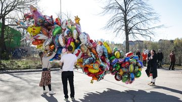 Perhe tutkii myynnissä olevia vappupalloja.