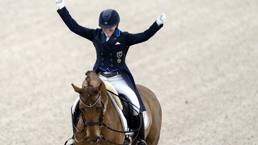Emma Kanerva tuulettaa kädet ylhäällä hevosen selässä.