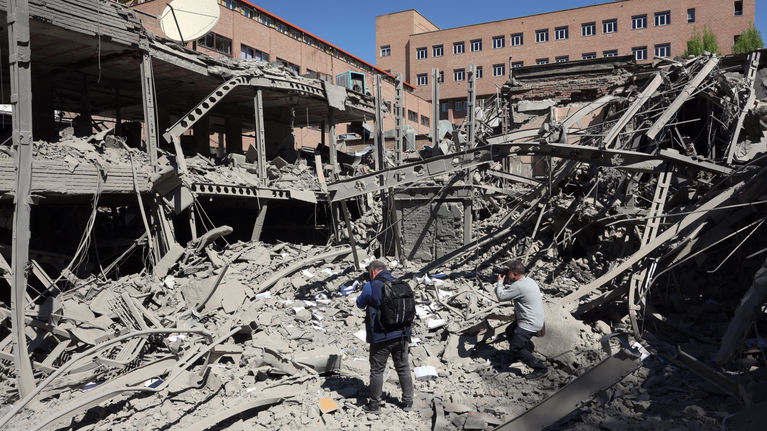 Journalists photographing the rubble of an apartment building.