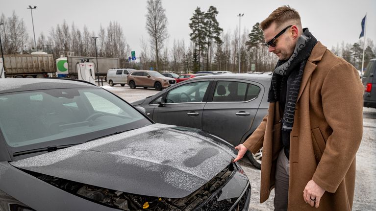 Iikka Laatu avaa auton konepeltiä.