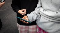 School girls stand next to each other with phones in their hands. 