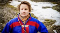 Niillas Holmberg. Taustalla lumilaikkuinen kallio.