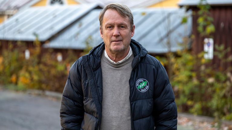 En leende man står med rocken uppknäppt.