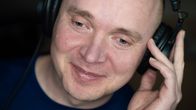 Petri Poikolainen lähikuvassa kuuntelee musiikkia luurit päässä.