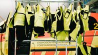 Ensihoidon kenttäjohtajan auton edessä roikkuu tangossa suojaliivejä.