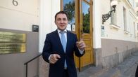 Tummaan pukuun pukeutunut Sosiaali - ja terveysministeri Wille Rydman seisoo valtioneuvoston juhlahuoneiston sisäänkäynnin edessä ja elehtii käsillään samalla kun puhuu.
