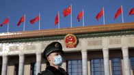 En ensam militär står framför Folkets stora hall i Peking.