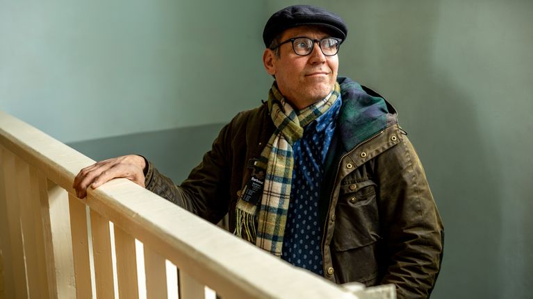 Juho har hatt och scarf och står inomhus vid ett räcke.
