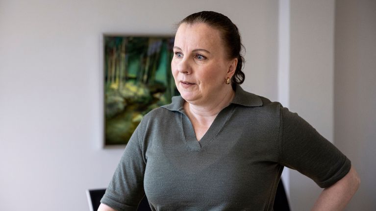 Hyvinvointialueen johtaja Sally Leskinen seisoo työhuoneellaan.