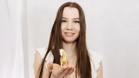 Nuori nainen pitää hymyillen kämmenellään Schleic-pienoishevosta,