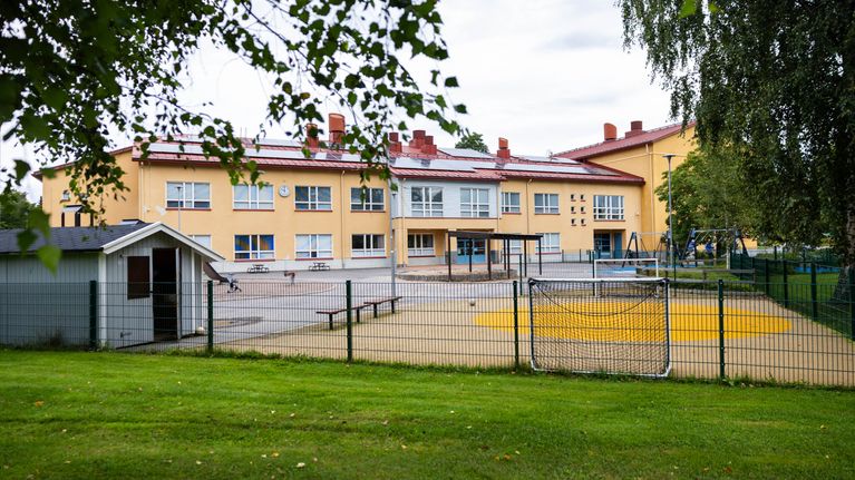 Stor gul stenbyggnad i två våningar med en lekplats och en stor gräsmatta framför. 