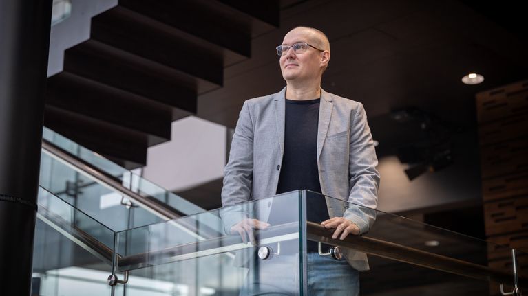 Reima Launonen seisoo ikkunaseinän vieressä.
