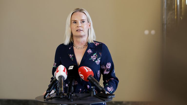 Riikka Purra puhuu mikrofonien takana pystypöydän ääressä.