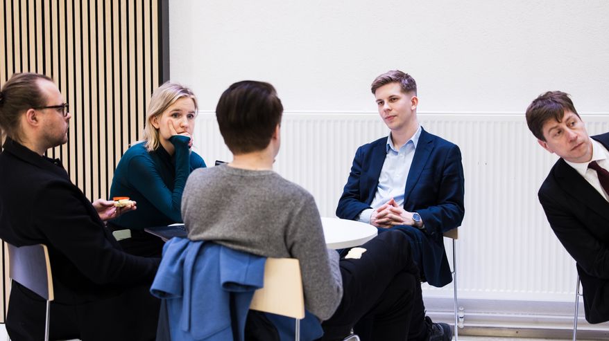 Joakim Vigelius keskustelee Julia Sangervon, Lauri Nevanperän ja Perttu Jussilan kanssa pöydän ääressä.
