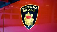 Pirkanmaan pelastuslaitoksen logo kuvattuna punaista paloauton kylkeä vasten.