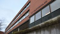 A modern building made of red bricks, lined with large windows. There is a sign that reads St Olofsskolan on the side of the structure.