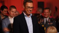Tasavallan presidentti Alexander Stubb seisoo yleisön joukossa koulun juhlasalissa.