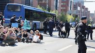 Poliisi ottaa kiinni mielenosoittajia. Taustalla bussi.