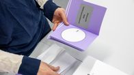 Henkilö selaa vaalikirjasta äänestyslipuketta, jossa lukee "Aluevaalit 2022 - Vaalipiirikohtaisesti".