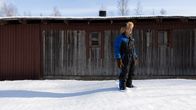 Vanha romanimies seisoo vanhan vajan edustalla. Hänellä on päällään toppahaalarit ja karvalakki.