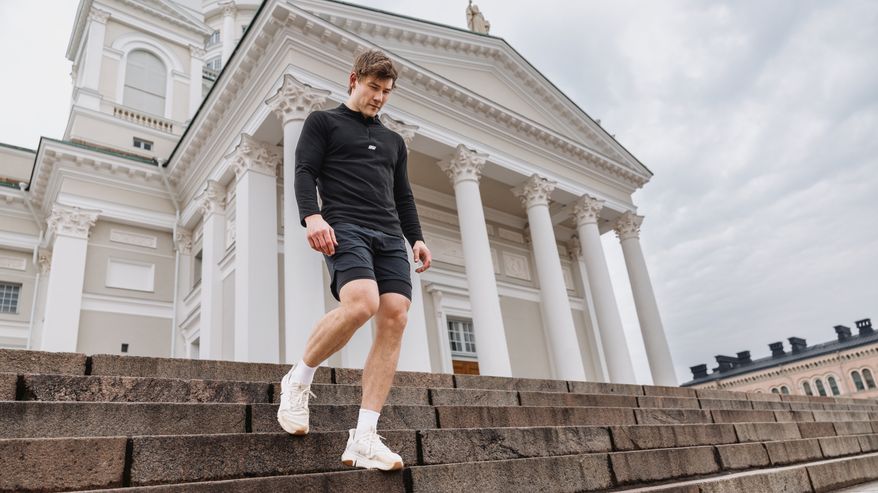 Mies kävelee alas portaita Helsingin tuomiokirkon edustalla pilvisenä päivänä.