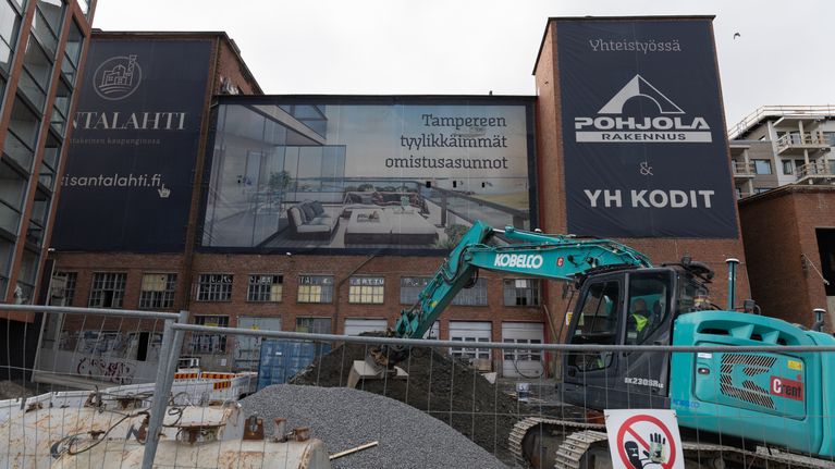 Rakennustyömaa Tampereella, jossa mainostetaan uusia omistusasuntoja.