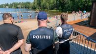 Poliser står vid en strand i Esbo. På ryggen av den ena står det "teknisk utredning". I bakgrunden syns simmande och solande människor.
