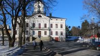 Två fotgängare går mot en vit byggnad.