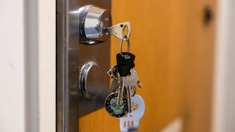 Keys with a skull-motif key fob hanging from a door lock.