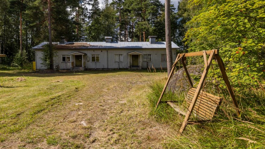 Keinutuoli ja vanha rakennus entisen leirikeskuksen alueella Suur-Miehikkälässä.