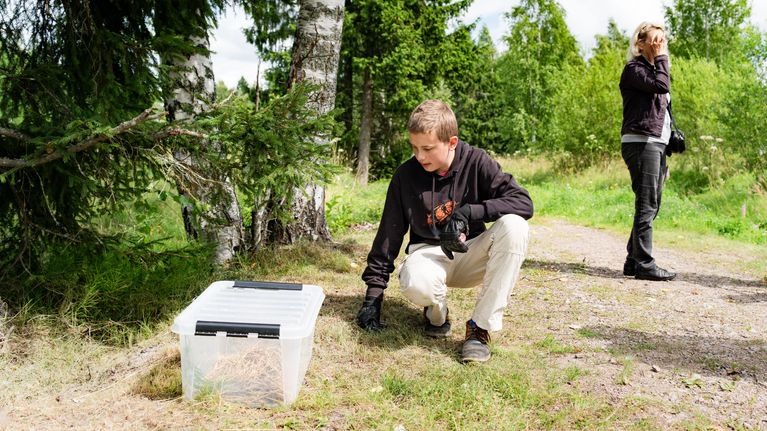En ung man på knä med en plastlåda på ett motionsspår.