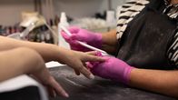 En nageltekniker arbetar koncentrerat med att forma kundens naglar med en nagelfil.