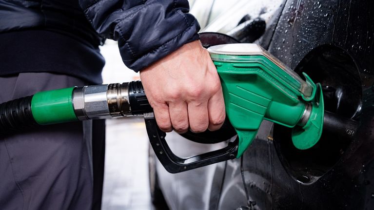 Henkilö tankkaa autoa vihreällä polttoainepistoolilla huoltoasemalla.