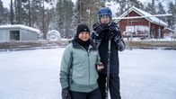 En kvinna och en pojke står i en hockeyrink med en puk och klubba i handen.