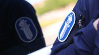 Poliisin hihamerkki heijastuu auton ikkunasta. 