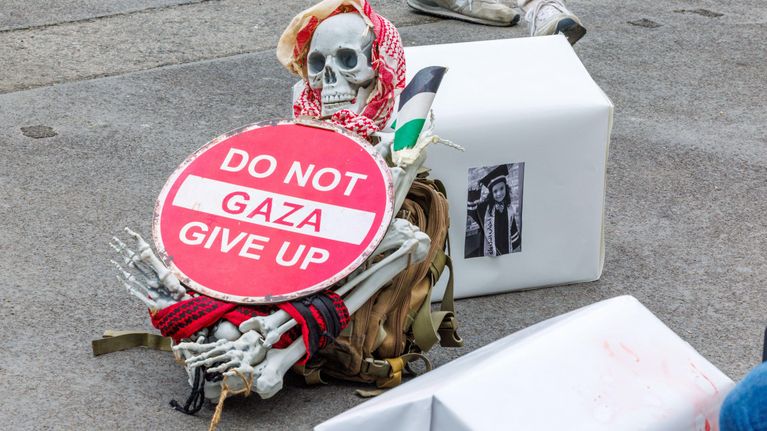 Luurankoon on kiinnitetty punavalkoinen kyltti, jossa lukee: Do not give up, gaza. Luurangolla on päässä palestiinalaishuivi ja kainalossa Palestiinan lippu.