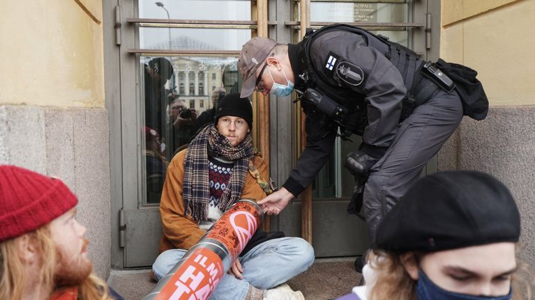 Poliiis yrittää poistaa mielenosoittajaa portailta.