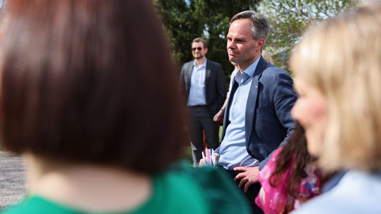 Ministeri Kai Mykkänen keskustelee ihmisten kanssa aurinkoisessa kevätsäässä.