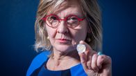 Virpi Hukkanen pitelee 2 eur kolikkoa ja katsoo kameraan.