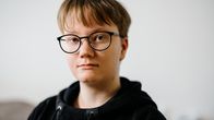 Nuori opiskelija katsoo kameraan.