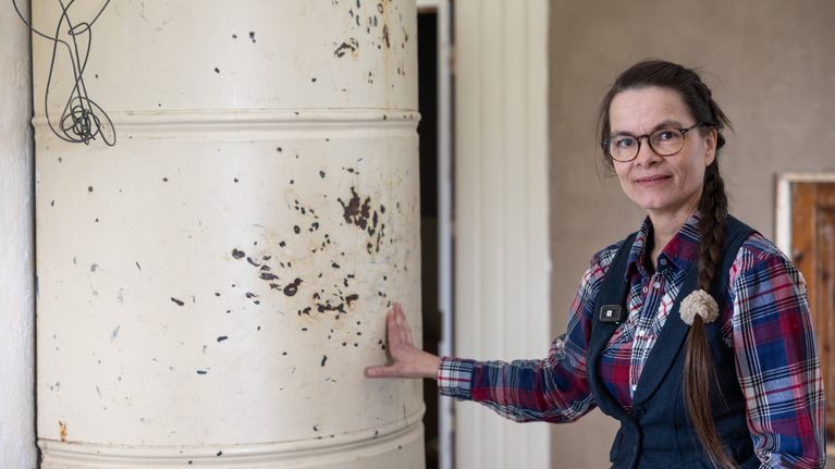 Monica visar hur den vita gamla kakelugnen har fått märken på sig.