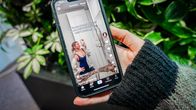 Henkilö katsoo puhelinta, jossa näkyy TikTok-video. Taustalla on viherkasveja.