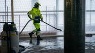 Rakennustyöläinen poistaa vettä imurilla välipohjasta rakennustyömaalla.