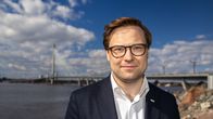 En leende man med mörkt hår och glasögon.