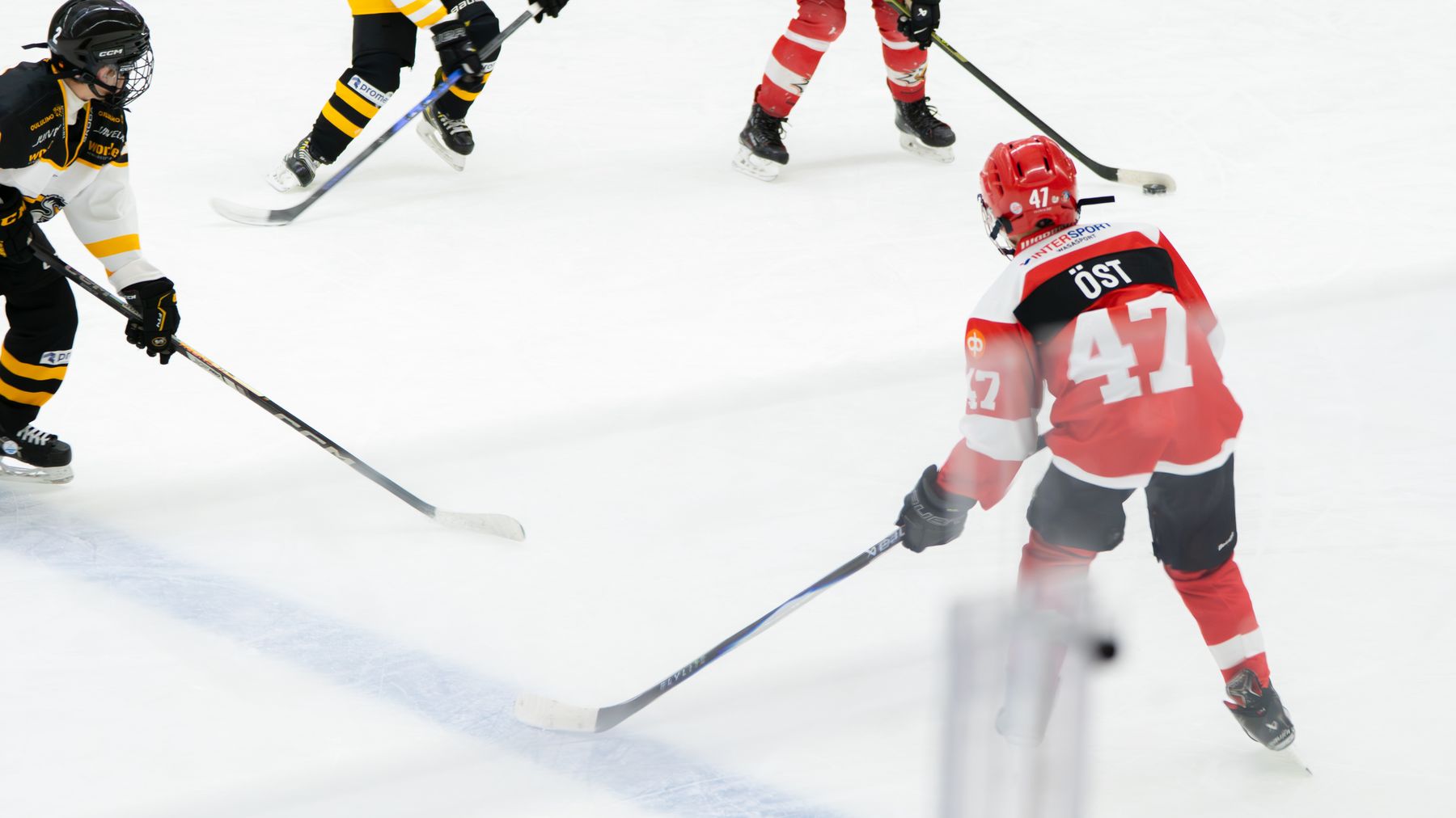 På bilden syns flera hockeyspelare under en match. Arthur Öst i Vasa Sports U12 har pucken.